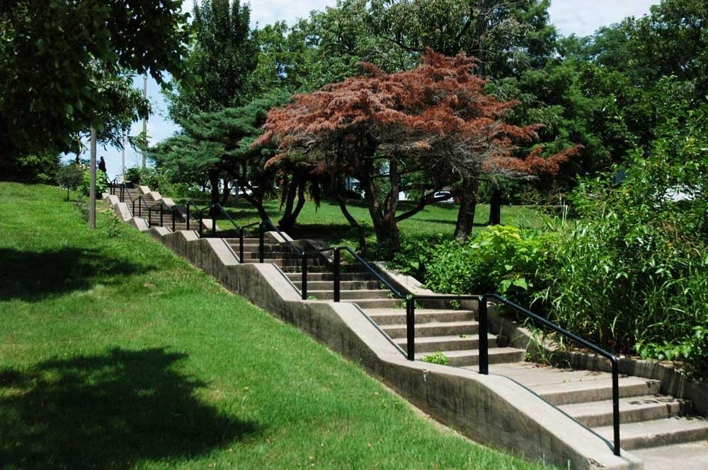 Stone steps with a handrail climbing through the trees at Clifton Heights Park