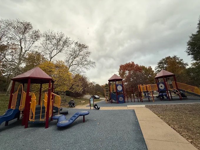 The playground at Clifton Heights Park in autumn, its climbing towers with red roofs and yellow rails